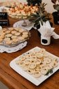 Assortment of delicious snacks and cookies arranged on white plates on a wood table Royalty Free Stock Photo