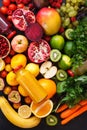 Assortment of different fruits and vegetables in rainbow colors with smoothies in bottles