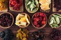 Assortment of dried fruits in spoons, bowls on brown wooden background. Royalty Free Stock Photo