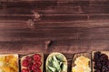 Assortment of dried fruits in spoons on brown wooden background. Royalty Free Stock Photo