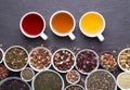 Assortment of dried tea leaves, fruit and herbs in bowls and cups of tea