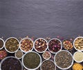 Assortment of dried tea leaves, fruit and herbs in bowls on dark, stone background Royalty Free Stock Photo