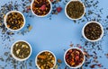 Assortment of dry tea in bowls on blue background. Flat lay style. Healthy, organic drink Royalty Free Stock Photo