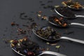 An assortment of dry tea in teaspoons, on a dark background. Red, fruit, green, black and herbal leaves are dried fresh dessert Royalty Free Stock Photo