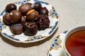 Assortment of fine filled chocolate bonbons on a plate with a cup of red tea Royalty Free Stock Photo