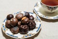 Assortment of fine filled chocolate bonbons on a plate with a cup of red tea Royalty Free Stock Photo