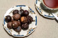 Assortment of fine filled chocolate bonbons on a plate with a cup of red tea Royalty Free Stock Photo