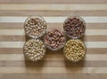 Five assorted raw legumes in bowls, placed on a chopping board