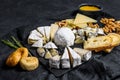 Assortment of French cheese with honey, nuts and figs on cutting board. Italian antipasto. Black background. Top view
