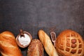 Assortment of fresh baked breads, top view bottom border on a dark background