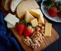 Assortment of fresh cheeses, strawberry, almond and walnuts on wooden table. Royalty Free Stock Photo