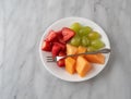 Assortment of fresh fruit with a fork on a white plate Royalty Free Stock Photo