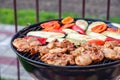 Assortment of fresh healthy colored vegetables, chicken meat grilled on BBQ grilling over a hot fire coals against green Royalty Free Stock Photo