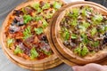 Assortment of fresh italian pizzas with ham, salami, meat, tomatoes, salad and parmesan on a wooden board on a wooden Royalty Free Stock Photo