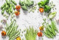 Assortment of fresh organic vegetables with copy space on a light background, top view. Asparagus, broccoli, green beans, peas, be