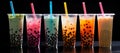 An assortment of fresh, vibrant boba arranged against a sleek black background. Plastic glasses filled with bubble tea