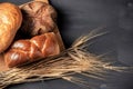 Assortment of freshly baked breads with ears of wheat on black background. Shallow depth of field. Royalty Free Stock Photo