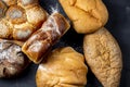 Assortment of freshly baked breads with ears of wheat on black background. Shallow depth of field. Royalty Free Stock Photo