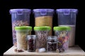 Assortment of groats and spices in plastic and glass jars on the wooden kitchen shelf