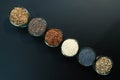 An assortment of healthy seeds chia, hemp flax, dill, sesame, poppy seeds - top view of small glass bowls against a black backgr