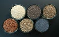 An assortment of healthy seeds chia, hemp flax, dill, sesame, poppy seeds - top view of small glass bowls against a black backgr
