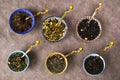 Assortment of herbal and natural dry tea in colorful small bowls and vintage silverware spoons