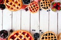 Assortment of homemade fruit pies. Overhead view double border over a white wood background.