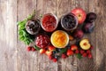 Assortment of jams, seasonal berries, plums, mint and fruits.