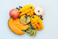 Assortment of juicy tropial fruit on white background. Slices on melon, orange mango, kiwi, lime, blueberries and apple.