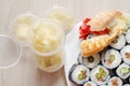 Assortment of maki rolls and tiger shrimp sushi. White spicy ginger in a plastic container. View from above