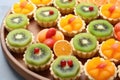 an assortment of mini tarts with kiwi, orange, and apple pieces Royalty Free Stock Photo