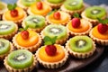 an assortment of mini tarts with kiwi, orange, and apple pieces Royalty Free Stock Photo