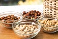 Assortment of mixed nuts and wicker basket on wood table background