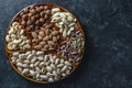 Assortment of nuts in ceramic bowl on a black background, close up, top view, copy space. Cashew, hazelnuts, pistachios and Royalty Free Stock Photo