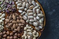 Assortment of nuts in ceramic bowl on a black background, close up, top view, copy space. Cashew, hazelnuts, pistachios and Royalty Free Stock Photo