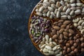 Assortment of nuts in ceramic bowl on a black background, close up, top view, copy space. Cashew, hazelnuts, pistachios and Royalty Free Stock Photo