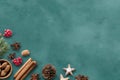 Assortment of nuts, cinnamon sticks, pine cones, and spices arranged on a green textured surface. Royalty Free Stock Photo