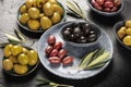 An assortment of olives. Green olives of various sizes, black and brown olives, and leaves