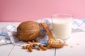 Assortment of organic vegan non dairy milk from nuts in glass on a wooden table on pink background. Coconut, almond nuts, spoon of