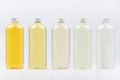 Assortment of plastic tall bottles with cosmetic essential oil of different pastel pale colors, silver cap mockup on white.