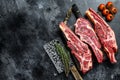 Assortment of raw cuts beef meat steaks on the bone. Black background. Top view. Copy space Royalty Free Stock Photo