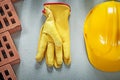 Assortment of red bricks hard hat protective gloves on concrete Royalty Free Stock Photo