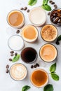 Assortment of refreshing coffee drinks in clear glasses with green leaves and coffee beans on white surface. Royalty Free Stock Photo