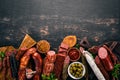 Assortment of salami and snacks. Sausage Fouet, sausages, salami, paperoni. On a black wooden background. Royalty Free Stock Photo