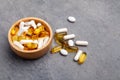 Assortment scattered pharmaceutical medicine tablets, pills, drugs in wooden bowl on gray background. White food dietary Royalty Free Stock Photo