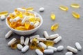 Assortment scattered pharmaceutical medicine vitamins, pills, drugs in bowl on gray background. White food dietary