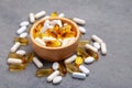 Assortment scattered pharmaceutical medicine vitamins, pills, drugs in wooden bowl on gray background. White food