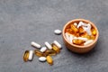 Assortment scattered pharmaceutical medicine vitamins, pills, drugs in wooden bowl on gray background. White food