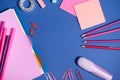 Assortment of school office accessories in pink shades, isolated on blue background, copy space. Copybook, felt tip pens, markers Royalty Free Stock Photo