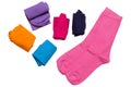Assortment of six pairs of socks in different colors, one laid out and the rest twisted, on a white background